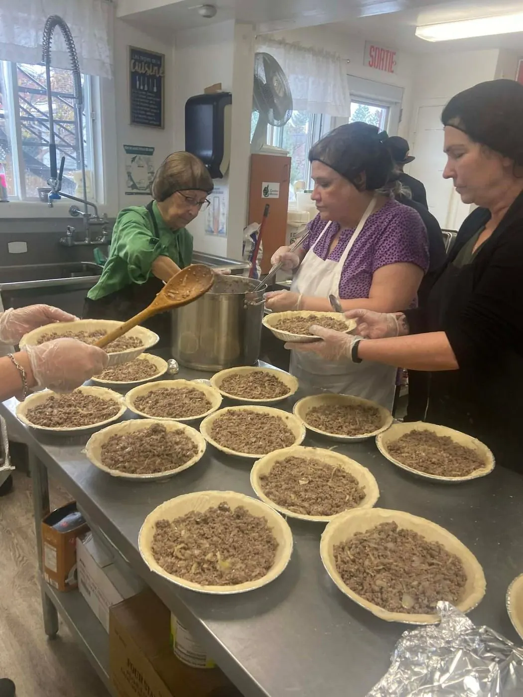 Des participantes préparent des dizaines de tourtières en cuisine collective